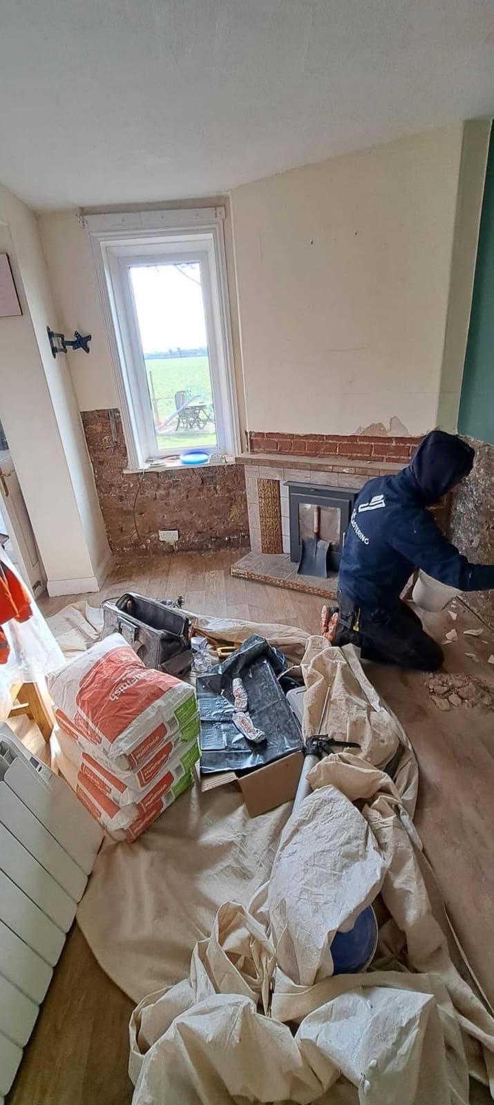 Callum stripping damp plaster back to brick beside a chimney breast