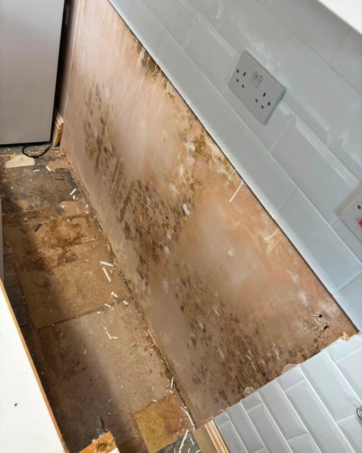 A kitchen wall in Middlesbrough, half stained with damp and mould and half freshly re-plastered by CK Damp Specialist