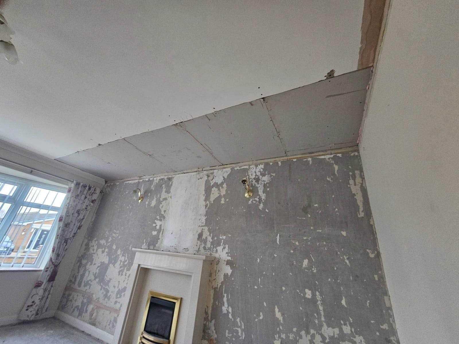 New plasterboard ceiling above stripped living room walls and a fireplace