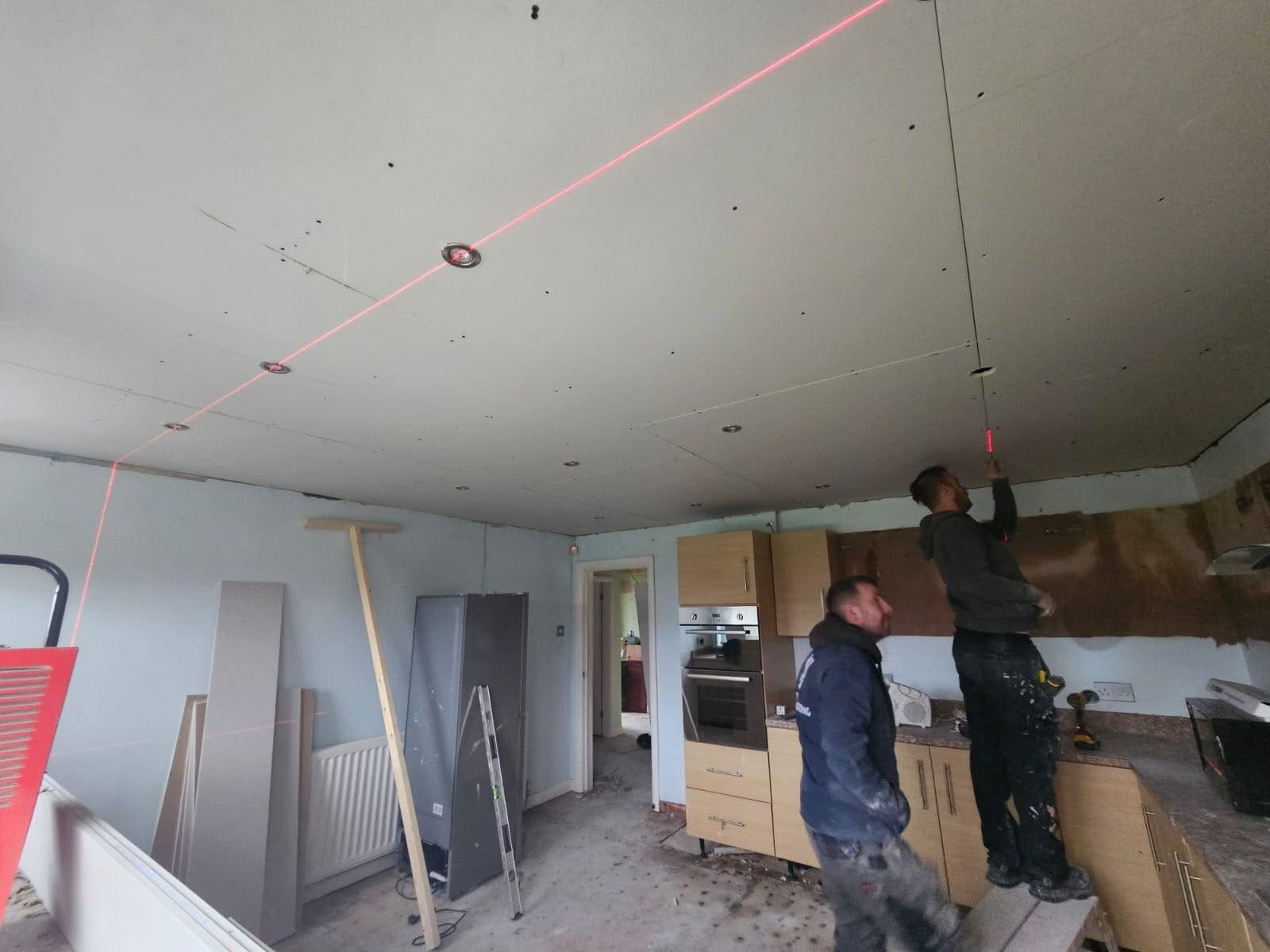 The CK team setting out a kitchen ceiling with a laser level