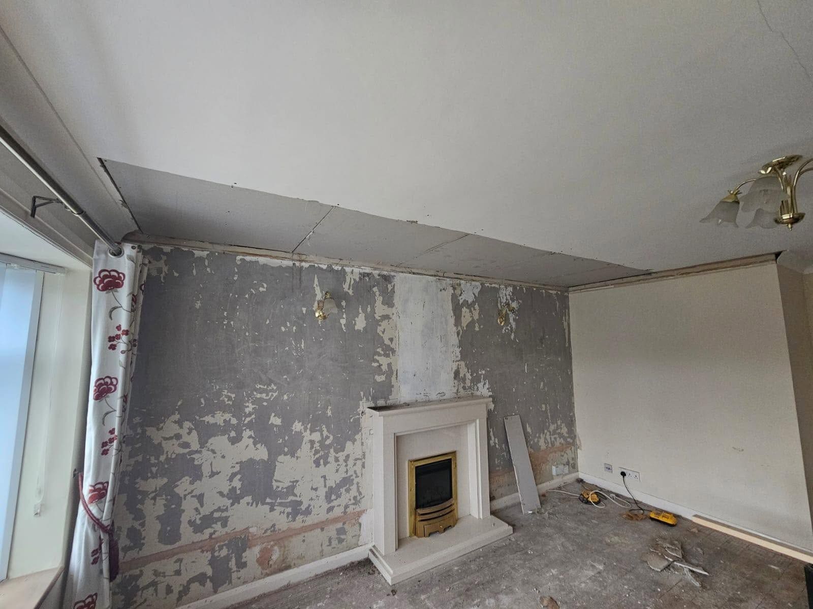 A living room stripped back with a new plasterboard ceiling and bare walls ready for plaster