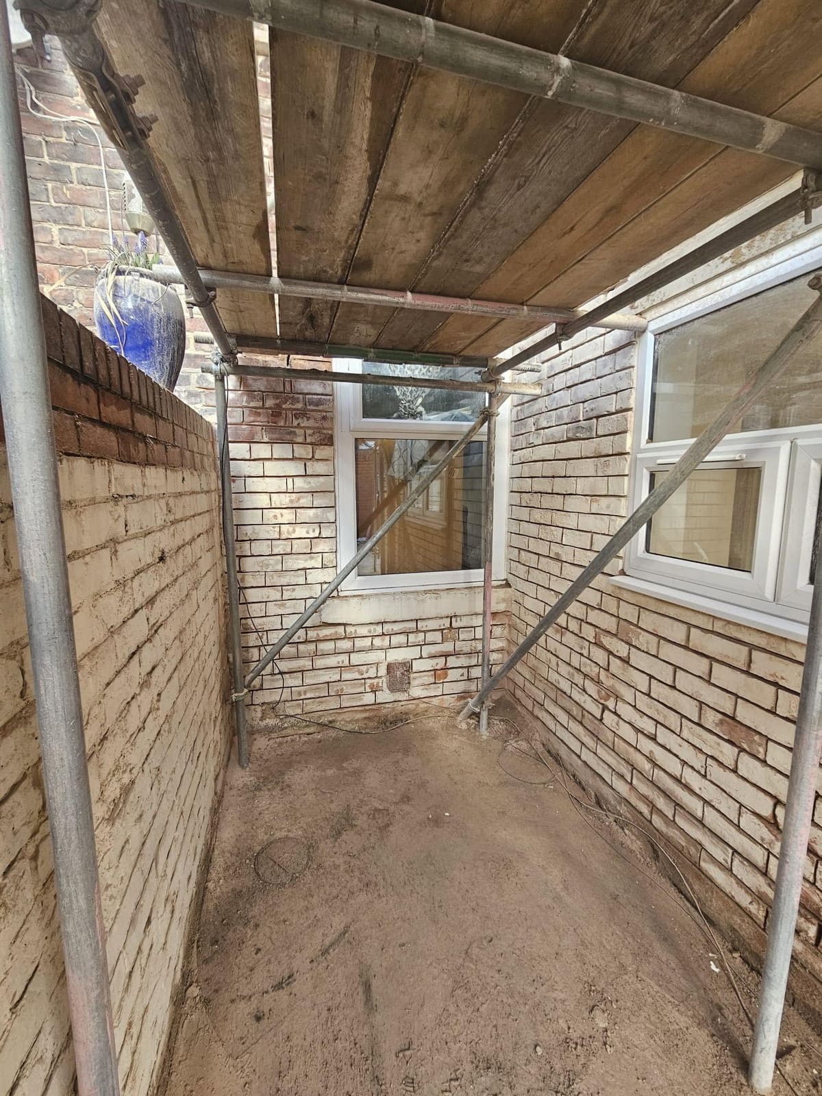 Ground-floor brickwork inside the scaffold beside a kitchen window
