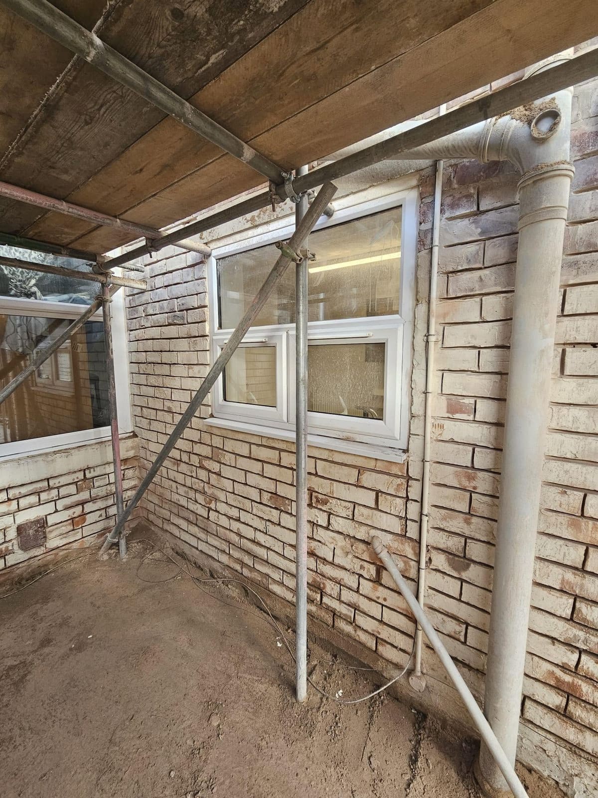 A bathroom window and downpipe on the prepared brick wall