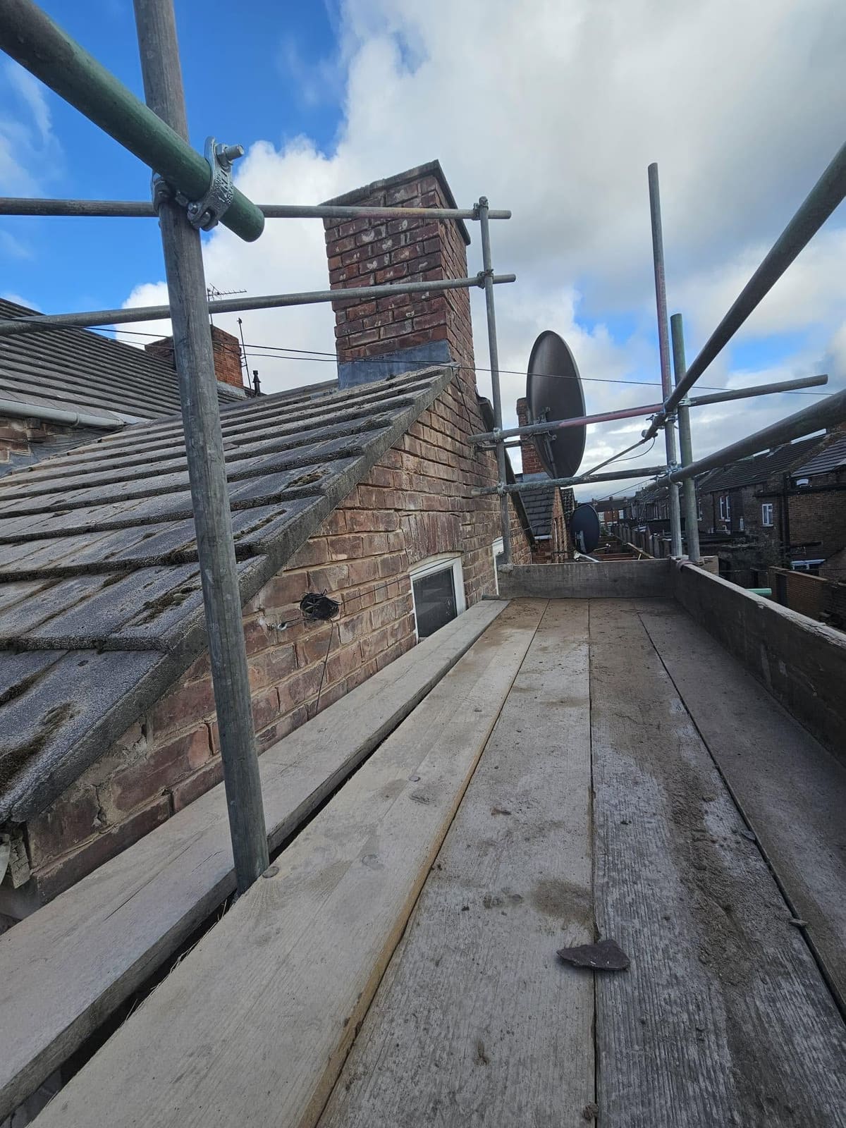 The scaffold at roof level beside the chimney stack
