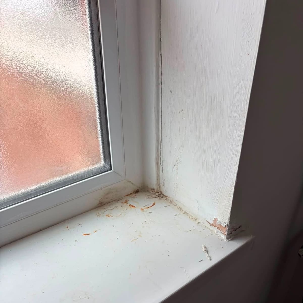 Staining and peeling paint at the corner of a bathroom window sill